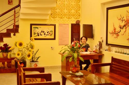 a woman sitting at a table in a room at Panda Garden Homestay in Hoi An