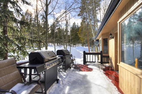 un patio cubierto de nieve con una parrilla y una casa en Gold King Lodge Home, en Breckenridge