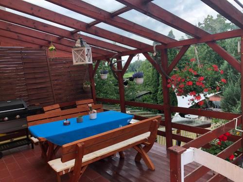 un patio de madera con una mesa azul y bancos en SeSil Apartman, en Pusztavám