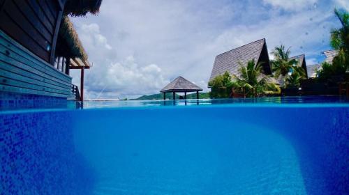 une grande piscine bleue à côté d'un complexe dans l'établissement Oa Oa Lodge, à Bora Bora