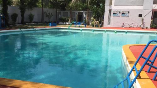 una gran piscina azul con 2 sillas azules. en Homestay Chateau 39, en Nueva Delhi