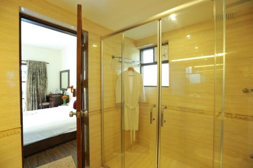 a glass shower in a bedroom with a bed at Deshadan Backwater Resort - The best sunrise view in Alleppey