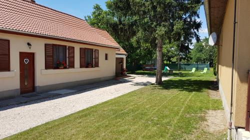 a house with a yard with a tree and a building at Ilona vendégház Dinnyés in Dinnyés