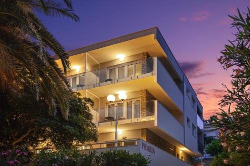 un edificio blanco con una puesta de sol en el fondo en Pharia Hotel and Apartments - by the beach, en Hvar