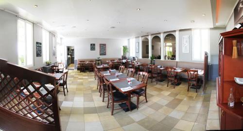 une salle à manger avec des tables et des chaises en bois dans l'établissement Hôtel de France, à Lillebonne