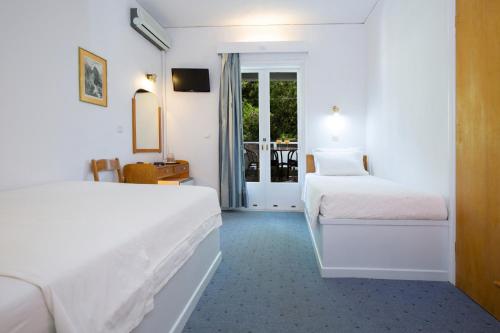 a hotel room with two beds and a balcony at Odyssey Hotel in Agios Nikitas