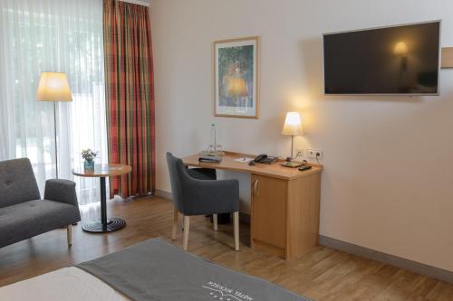 ein Hotelzimmer mit einem Schreibtisch und einem TV an der Wand in der Unterkunft Hotel Nickisch in Schüttorf