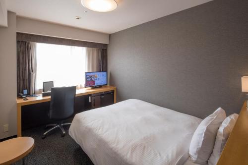 a hotel room with a bed and a desk with a computer at Richmond Hotel Kumamoto Shinshigai in Kumamoto