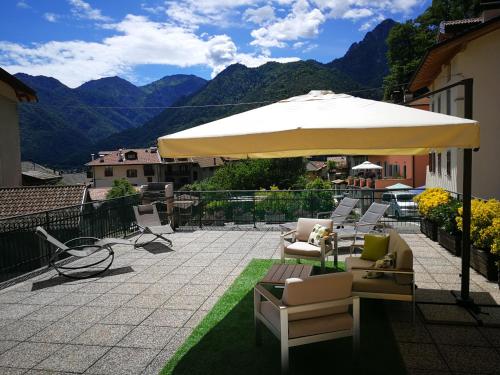 a patio with a large umbrella and chairs and tables at Casa Luca e Cristina in Mezzolago