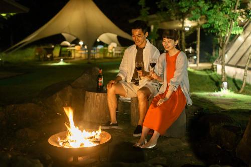a man and a woman sitting next to a fire at The Day Osaka in Osaka