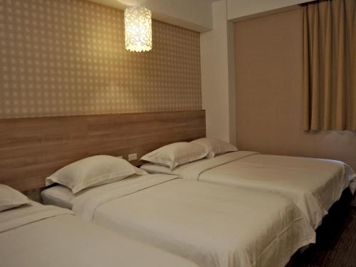 two beds in a hotel room with at The Riverside Hotel Hengchun in Hengchun