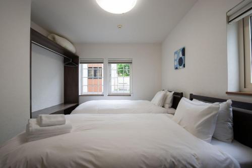 three beds in a room with white sheets at Asuka in Kutchan