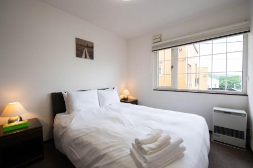 a bedroom with a white bed with two white towels on it at Asuka in Kutchan