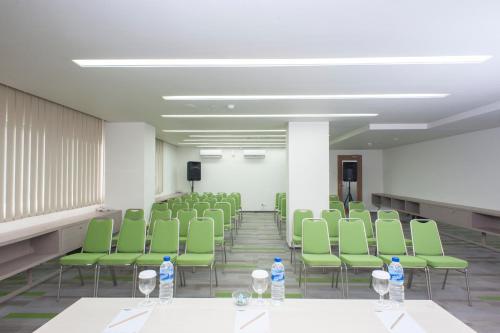 a room with green chairs and bottles of water on tables at MaxOneHotels at Dharmahusada Surabaya in Surabaya