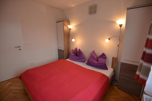 a bedroom with a red and white bed with purple pillows at PirkerHof in Wenischgraben