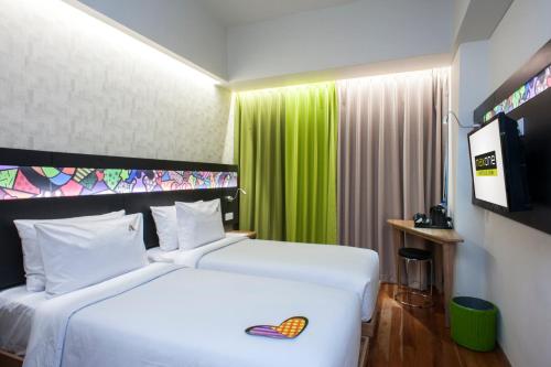 a hotel room with a white bed and a green curtain at MaxOneHotels at Dharmahusada Surabaya in Surabaya