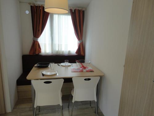 a dining room table with two chairs and a window at Camping les Acacias in Fréjus