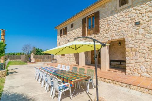 a table with chairs and an umbrella in front of a building at Son Pujol in Montuiri