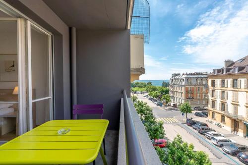 a yellow bench on a balcony with a view of a street at Hôtel Des Arts in Neuchâtel