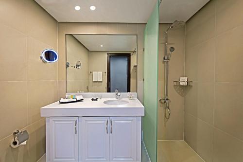ドーハにあるThe Curve Hotelの白い洗面台とシャワー付きのバスルーム