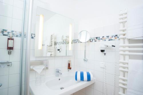 a white bathroom with a sink and a mirror at Strandhaus am Inselsee in Güstrow