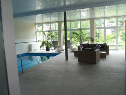 ein Wohnzimmer mit einem Pool, Stühlen und Fenstern in der Unterkunft Zum Belzenikel in Dernbach