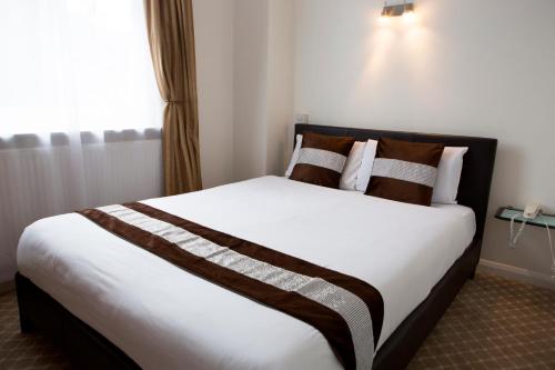 a bedroom with a large white bed with brown pillows at Westpoint Hotel in London