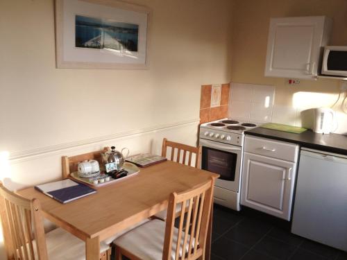 a small kitchen with a wooden table and a stove at Wheal Rodney Holiday Park in Marazion