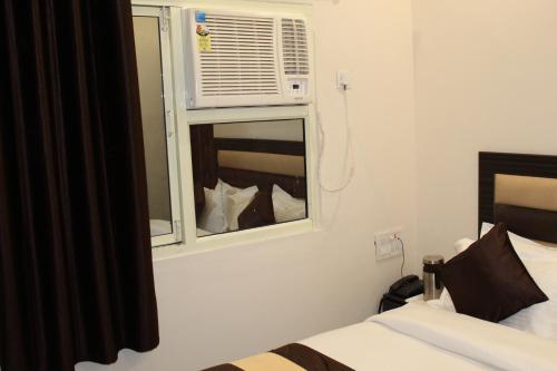 a bedroom with a bed and a window with an air conditioner at Hotel Gopal in Haridwār