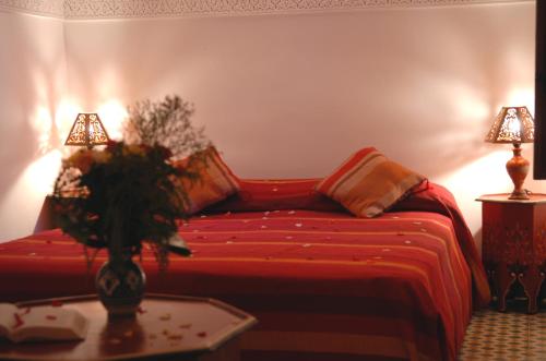a bedroom with a red bed with two lamps and a table at Riad Mehdia in Marrakech