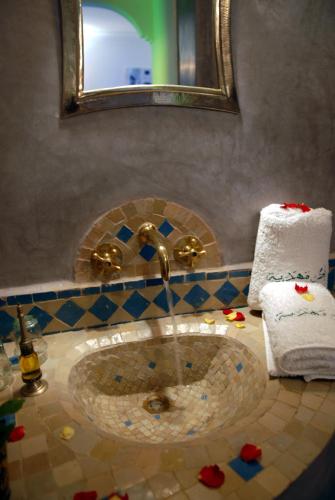 a bathroom with a sink with a mirror and towels at Riad Mehdia in Marrakech