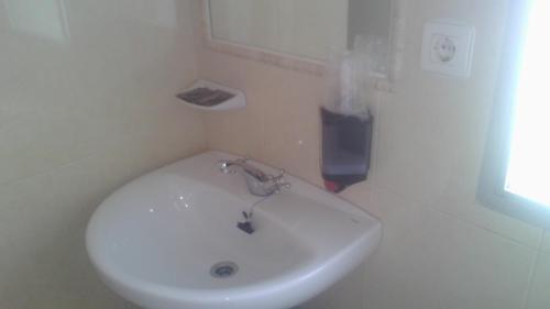 lavabo blanco en un baño con ventana en Hostal Cabrera, en Motril
