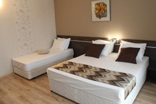 two beds in a hotel room with white sheets at Sea & Hill Guest Houses хотелски тип in Lozenets