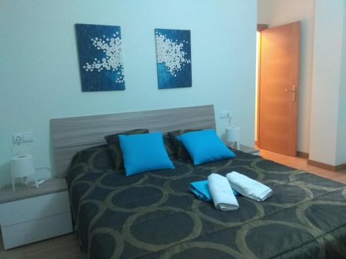 a bedroom with a large bed with blue pillows at Caminito ARG in La Bañeza