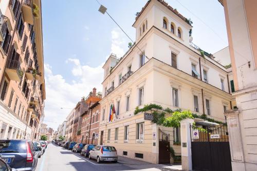 een hoog wit gebouw op een straat met geparkeerde auto's bij Hotel Celio in Rome