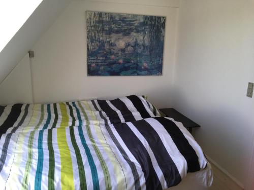 a bed in a bedroom with a painting on the wall at Thurø Rev Guesthouse in Svendborg
