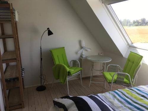 a bedroom with green chairs and a table and a window at Thurø Rev Guesthouse in Svendborg