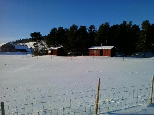 a snow covered field with buildings and a fence at Borkhushyttene in Rundtom