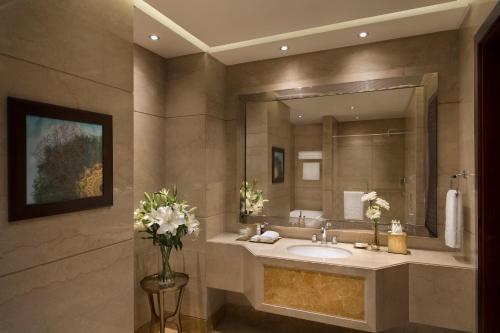 
a bathroom with a marble counter top and a large mirror at Al Najada Doha Hotel by Tivoli in Doha
