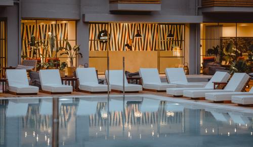 a hotel lobby with a pool and white lounge chairs at Cook's Club Hersonissos Crete in Hersonissos
