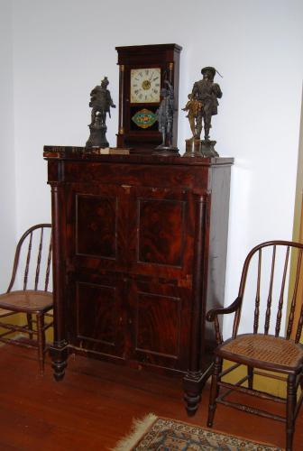 a wooden cabinet with a clock and two chairs at Glenfield Plantation Historic Antebellum Bed and Breakfast in Natchez