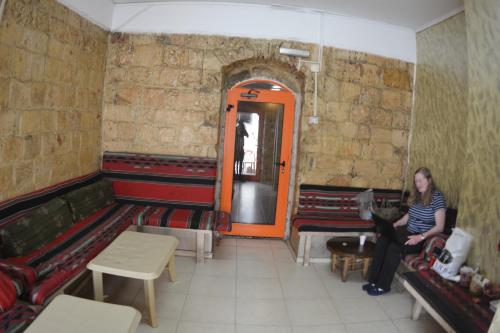 a woman sitting on a couch in a room with red benches at Palm Hostel in Jerusalem