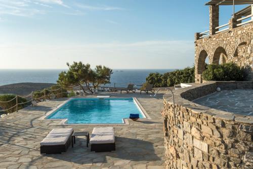 a swimming pool with two benches next to a building at Terra in Parikia