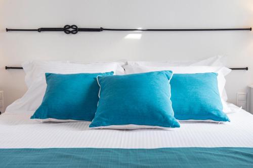 a bed with three blue pillows on it at Terra in Parikia