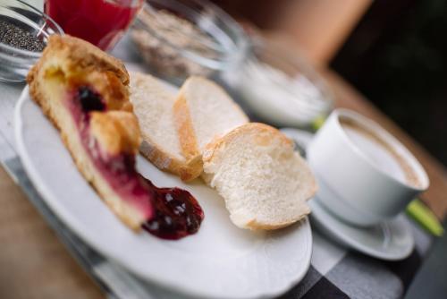 a white plate with a sandwich and bread and jam at Hotel Rendez Vous in Châtillon