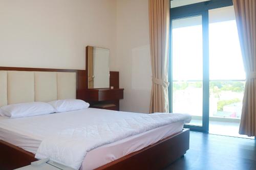 a bedroom with a bed with a mirror and a window at My Ca Hotel in Cam Ranh