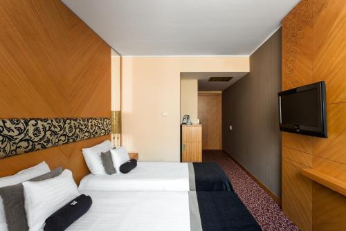 a hotel room with two beds and a flat screen tv at Marmara Hotel Budapest in Budapest