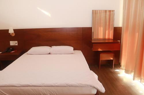 a bedroom with a white bed and a desk at My Ca Hotel in Cam Ranh