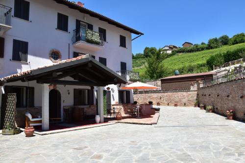 a large white building with an umbrella and a patio at B&B La Dolce Vita in Priocca