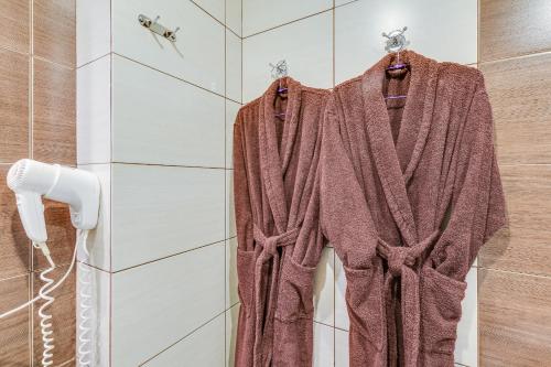 a robe hanging in a shower in a bathroom at Veles Hotel in Saint Petersburg